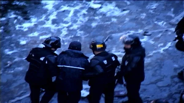 In a snowy lot, four police look at the ground.