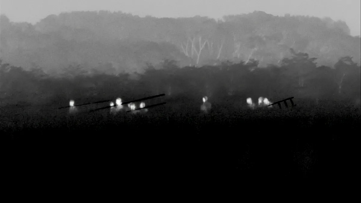 A black and white image of a group of people moving through the dark.