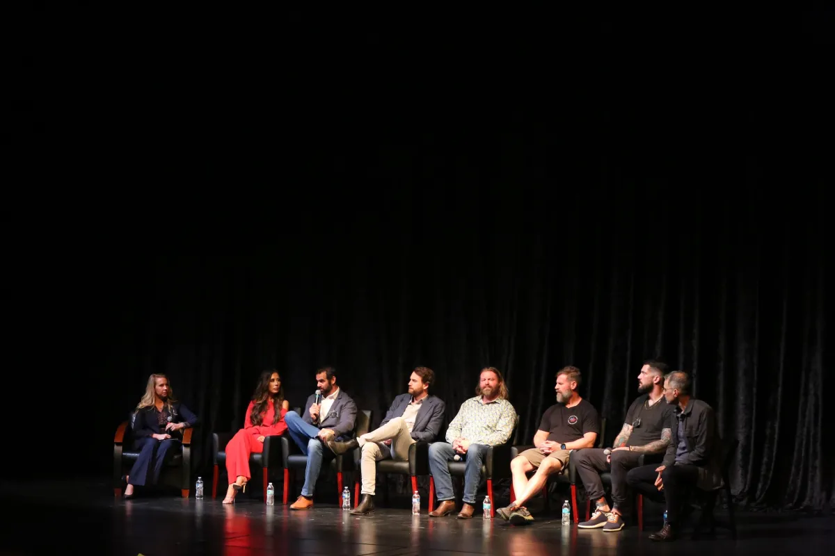 Seven panelists and one moderator sit on stage.