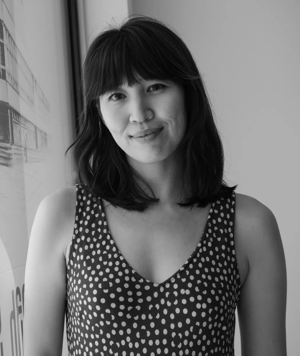 A black and white headshot of a light-skinned woman with dark hair wearing a sleeveless dotted dark dress