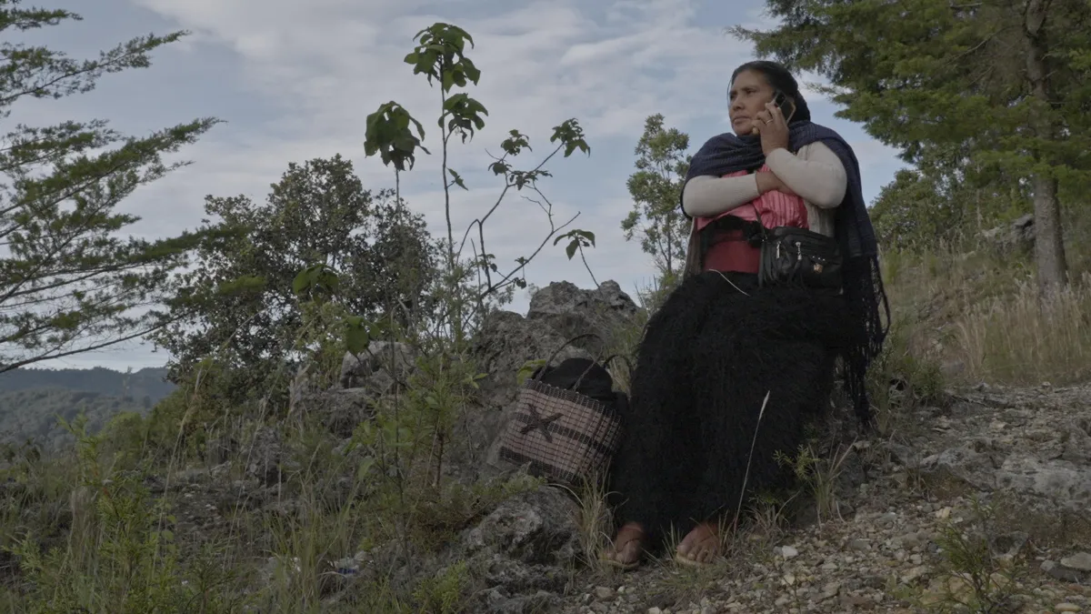  Mariano´s mother in her traditional clothes from Chamula and surrounded by the mountains of his home town calls him by cellphone. 