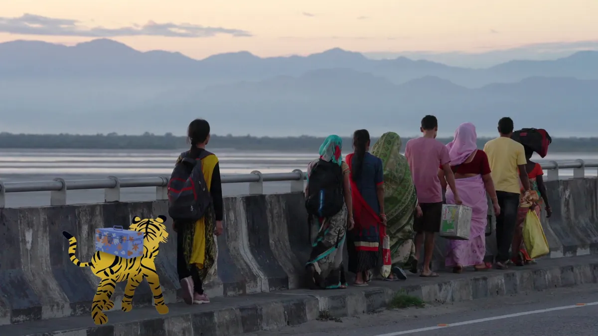 A group of men in colorful shirts and women in colorful saris walk along a sidewalk on a bridge, mountains in the distance, with an animated tiger with a backpack picking up the rear