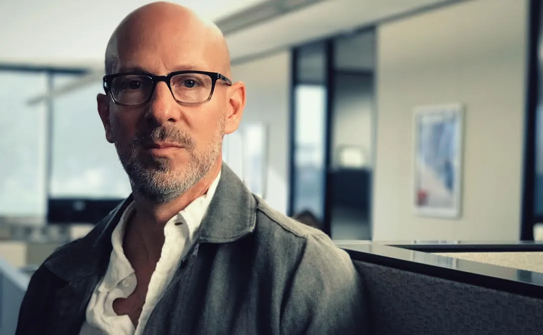 A man with white skin looks at the camera. He wears glasses, a grey jacket, white shirt and is bald and has a light beard. Headshot of Joshua Seftel