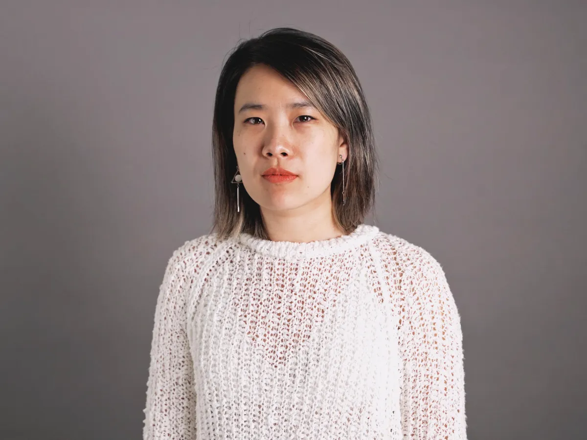Portrait of an Asian woman with shoulder-length hair and wearing a white sweater.