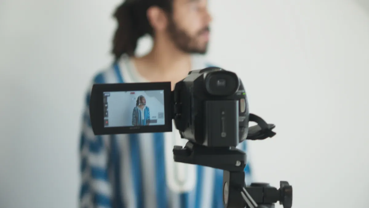 A man turns away from the camera, against a white wall.