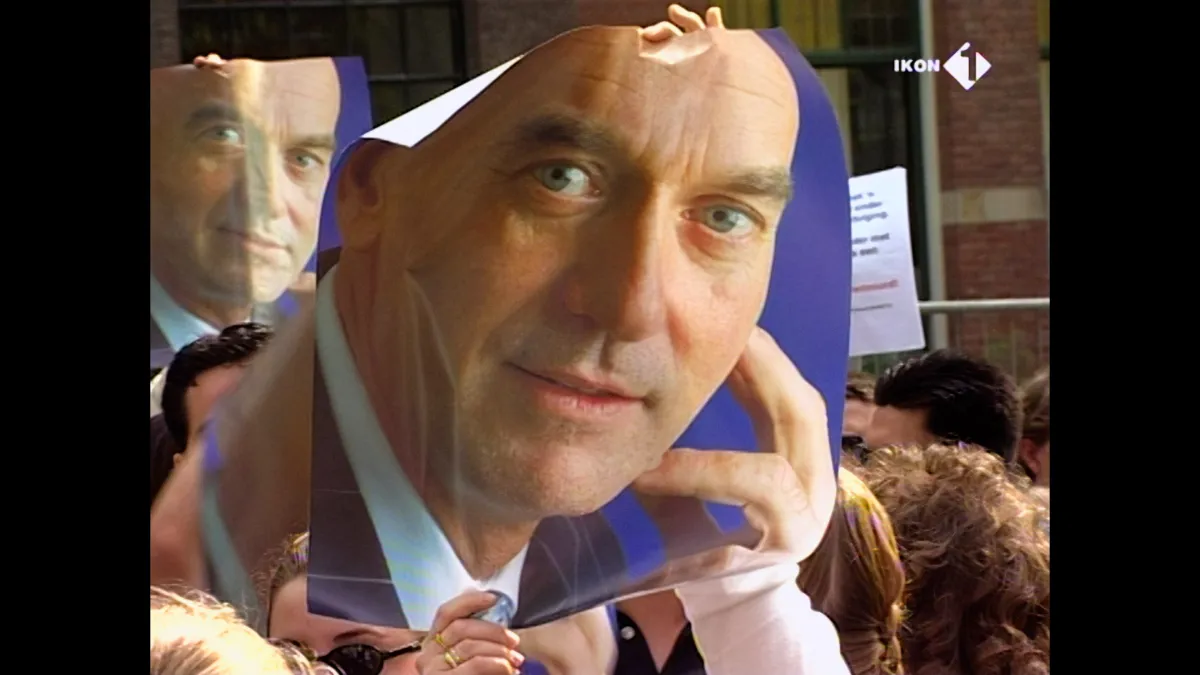 A poster of a white bald freshly-shaven man is being held up by a crowd