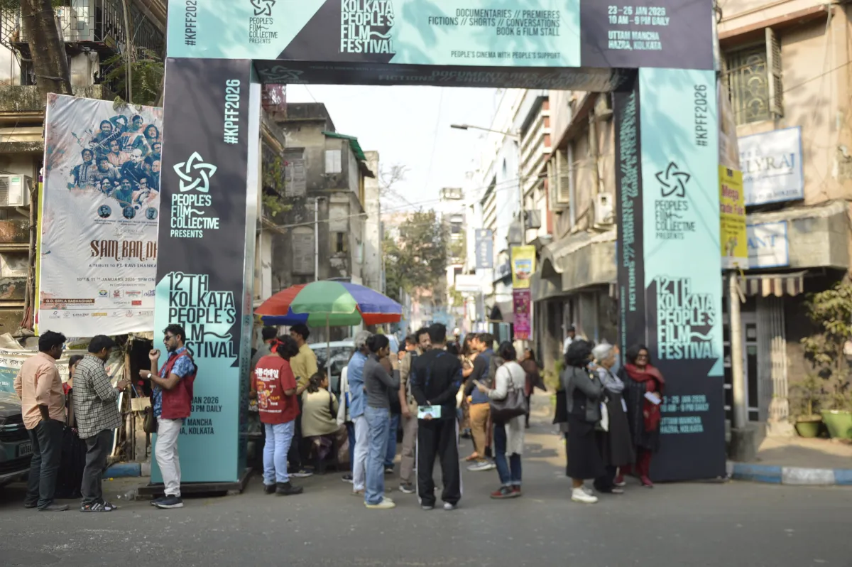 Wide shot of an open street adorned with Kolkata People's Festival banners with various people milling around