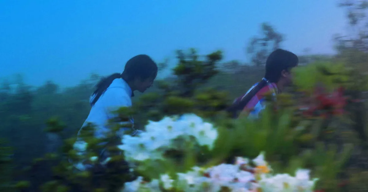 Wildly saturated photo of two young girls with long black hair walking in a meadow filled with flowers