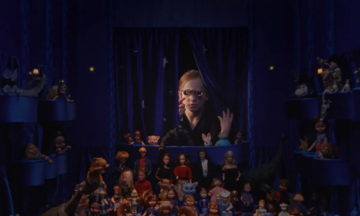 A blonde girl peers through spectacles into a space enclosed in purple curtains filled with various dolls