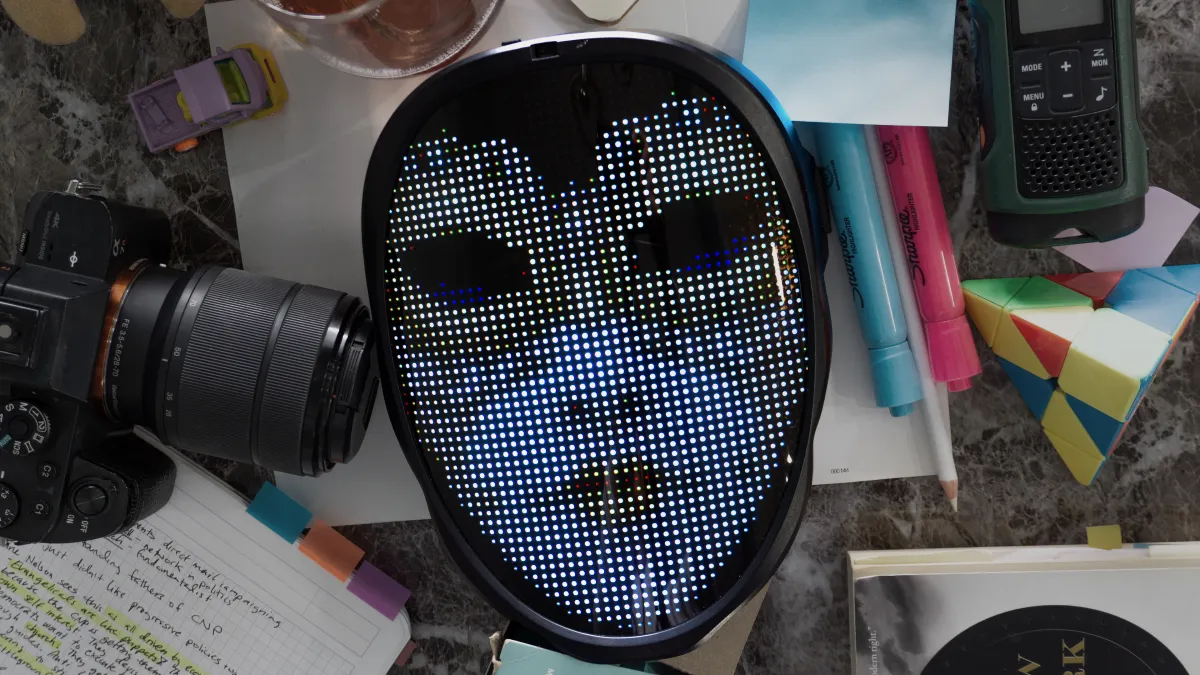 A picture of several items on a table including; A mask that one mom wears in the film, a camera, pens, sticky notes, and several other small items.