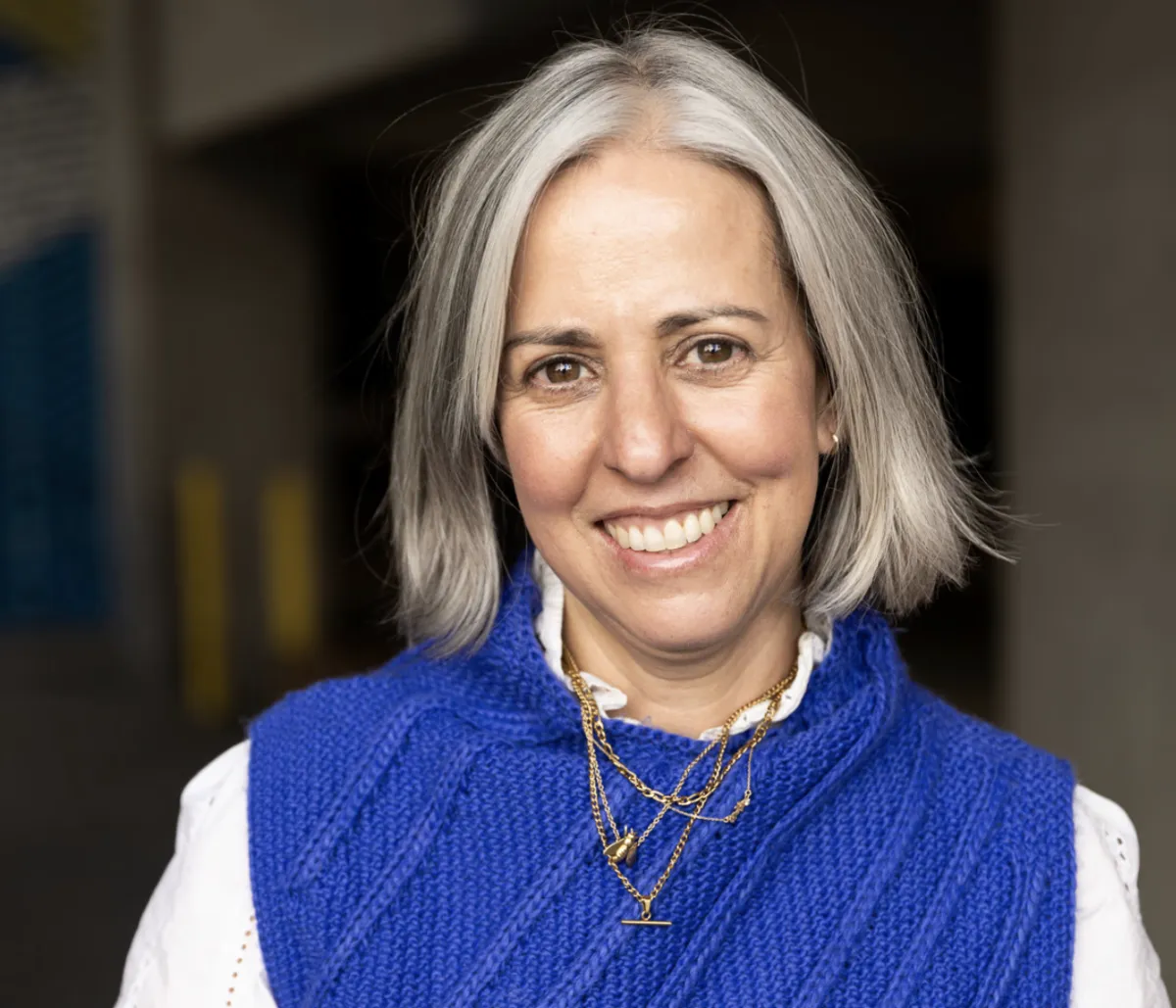 Headshot of Jennifer Sofio Hall. Fair skinned woman with a blue sweater and white shirt. Shoulder length hair and a wide smile.
