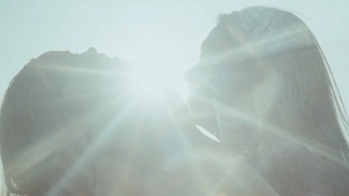 A mother and her daughter embrace in the glare of sunlight.