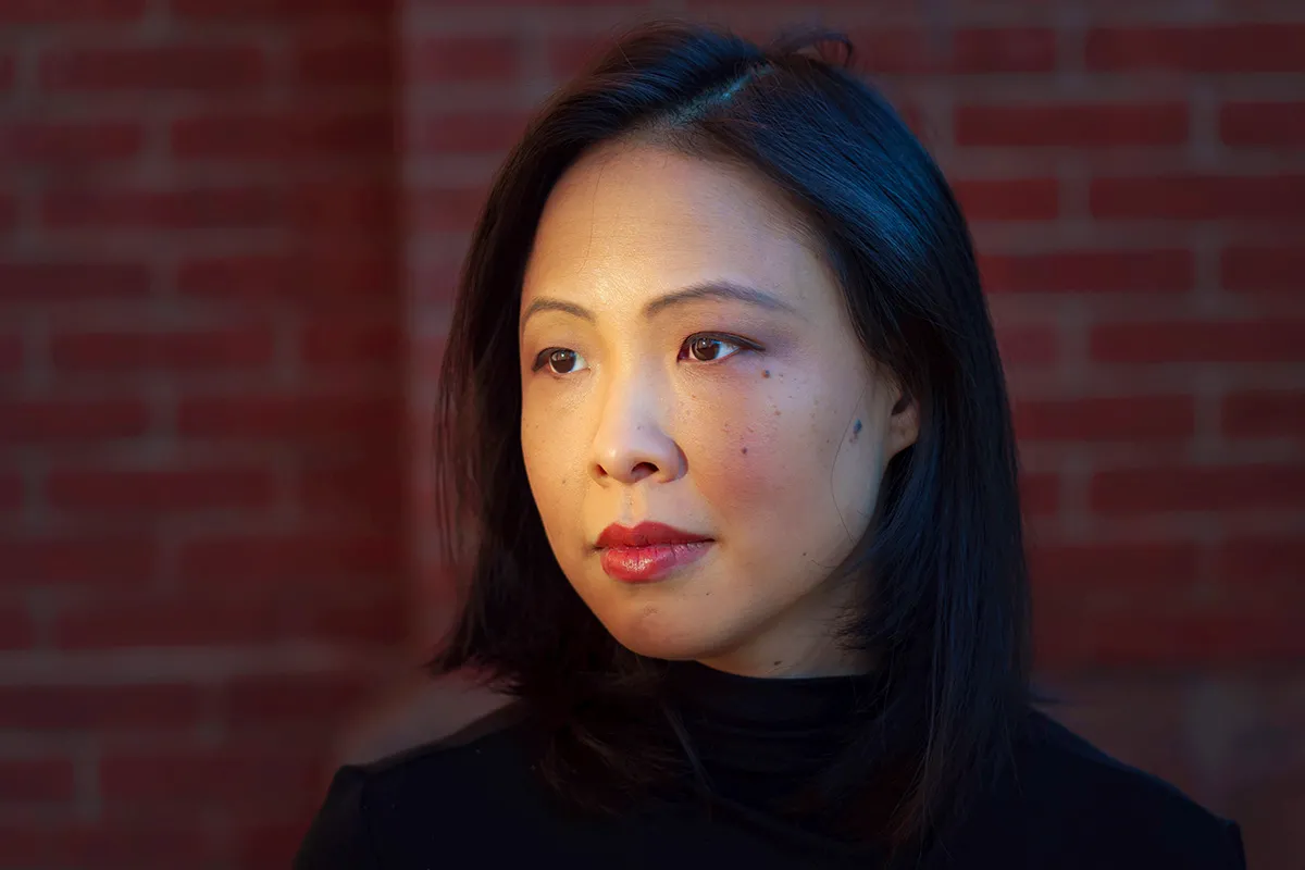 Poh Si Teng is an Asian woman of Malaysian Chinese origin with shoulder-length black hair. She is wearing a black turtleneck & in front of a brick wall. Photo by Marcus Yam