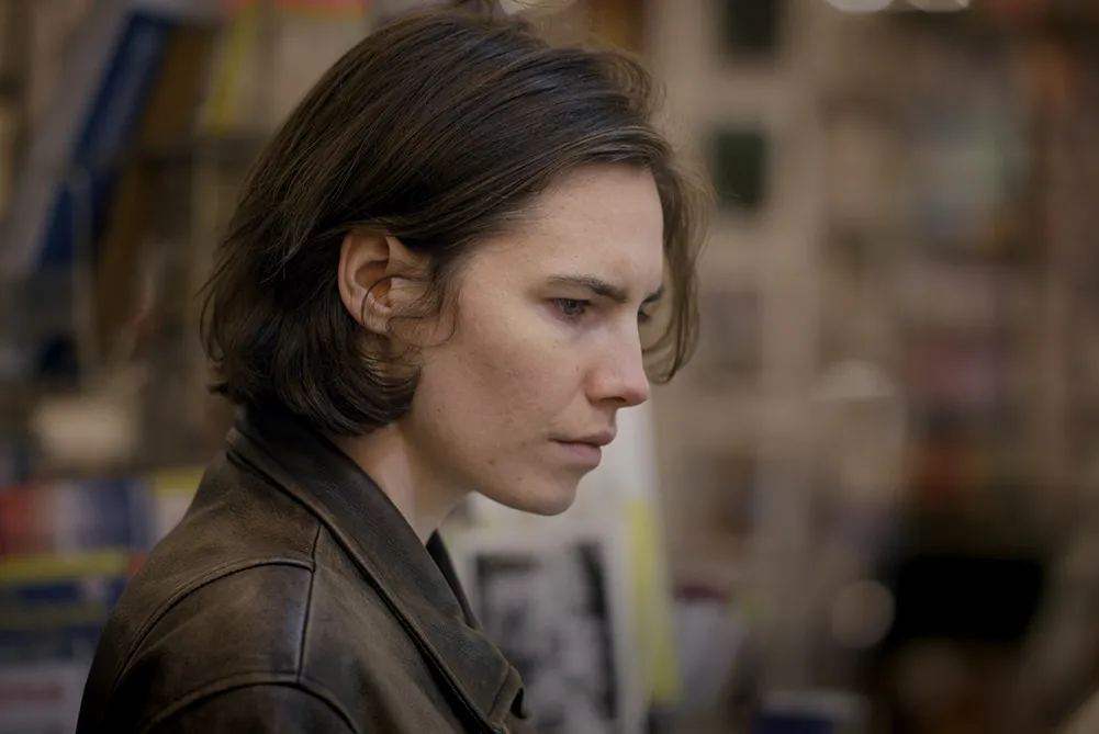 Side profile of Amanda Knox, a white woman with short brown hair. She is wearing a leather jacket. Image from from Ron Blackhurst and Brian McGinn's 2016 film ‘Amanda Knox.’ Courtesy of Netflix.