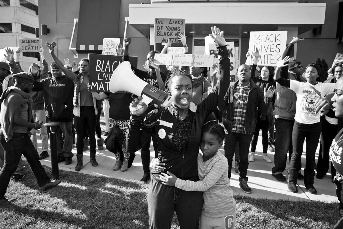 A Black woman with a megaphone raises her arm and shouts in a crowd of people. From Sabaah Folayan's 'Whose Streets?', a Magnolia Pictures release. Photo courtesy of Magnolia Pictures.