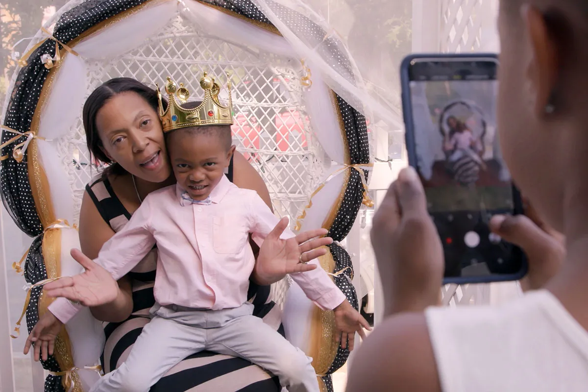 Shanona is a middle-aged Black woman, seen here holding her son, a Black boy wearing a gold toy crown. From Loira Limbal’s ‘Through the Night.’ Photo by Naiti Gámez. Courtesy of POV.