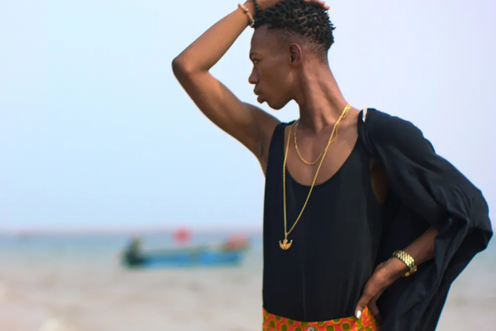 James, a young activist with Black skin wearing a black tank top, orange pants and gold jewelry, looks off behind him. A still from the film 'The Legend of the Underground.' Courtesy of HBO. 