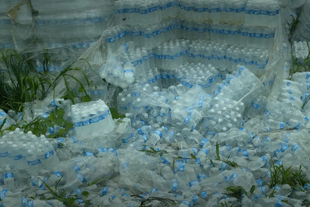 Hundreds of undistributed plastic bottles of water lying on the ground in Puerto Rico. Image from “Landfall,” directed by Cecilia Aldarondo. Photo by Pablo Alvarez-Mesa. Courtesy of POV