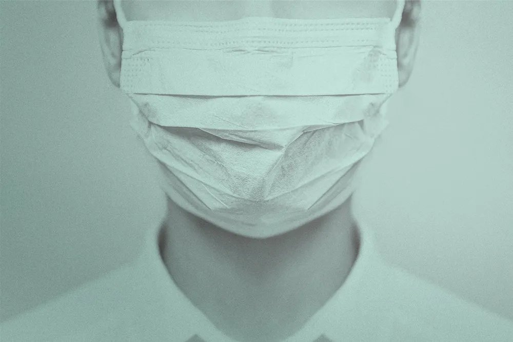 A close up shot of a woman with white skin wearing a white face mask.