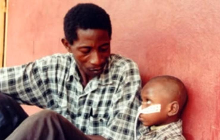 A man looks down at a young child with a tube in his nose, from Thierry Michel's 'Donka, X-Ray of An African Hospital  (Donka, radioscopie d'un hopital africain).'