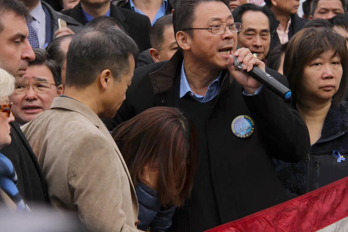 An activist, holding a microphone and wearing a black blazer over a blue shirt, addresses a protest in Brooklyn, New York.