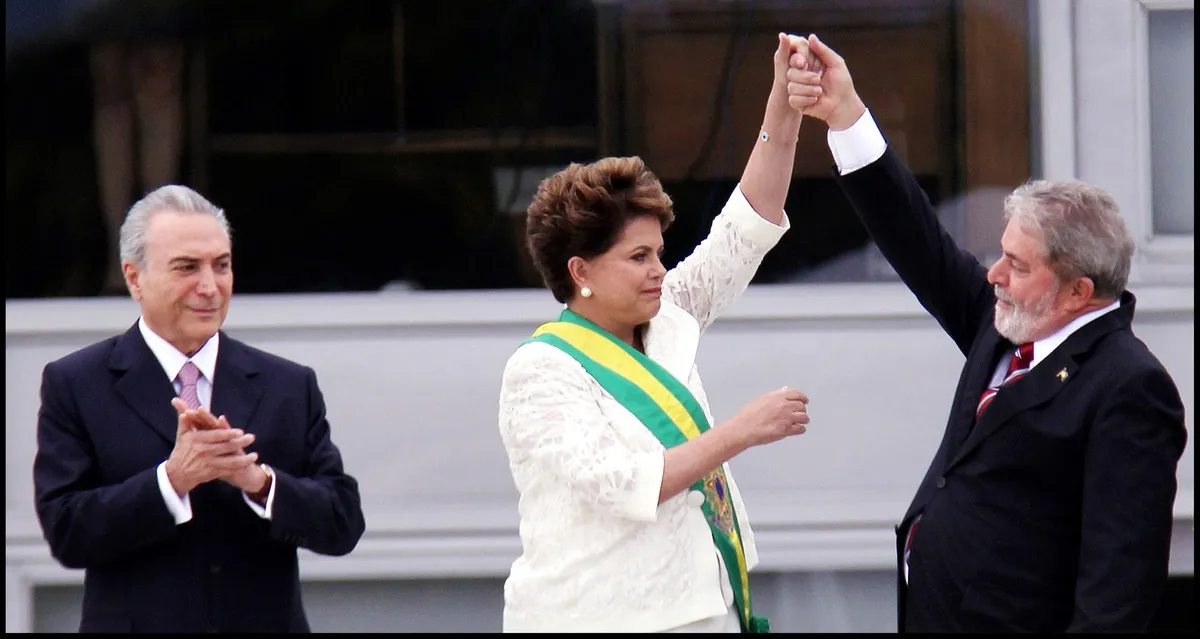 Dilma Rousseff, the former president of Brazil, is applauded  while  Luiz Inácio Lula da Silva, her predecessor, who was just elected president for the second time, on October 30, 2022, raises her hand in the air. From Petra Costa’s ‘The Edge of Democracy.’ Photo courtesy of Netflix. 