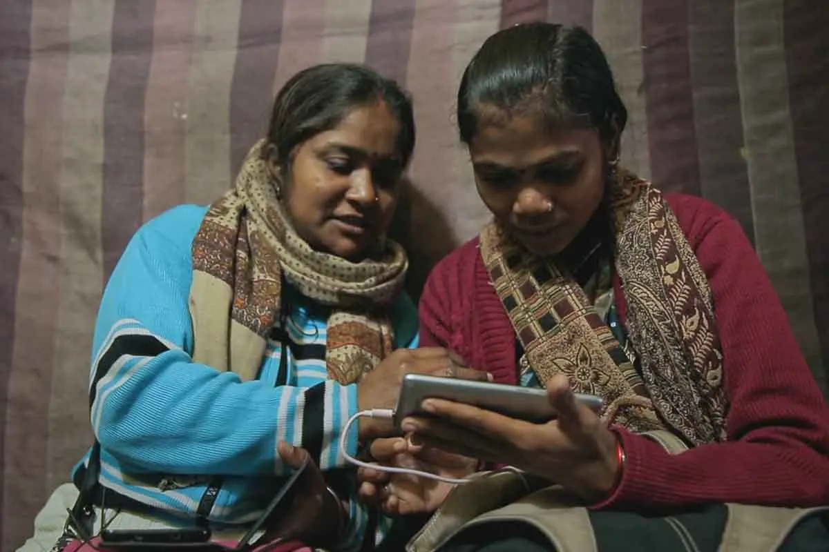 Meera and Shyamkali are two South Asian journalists looking at filmed footage on a cellphone. From Rintu Thomas and Sushmit Ghosh’s ‘Writing With Fire.’ Courtesy of Music Box Films