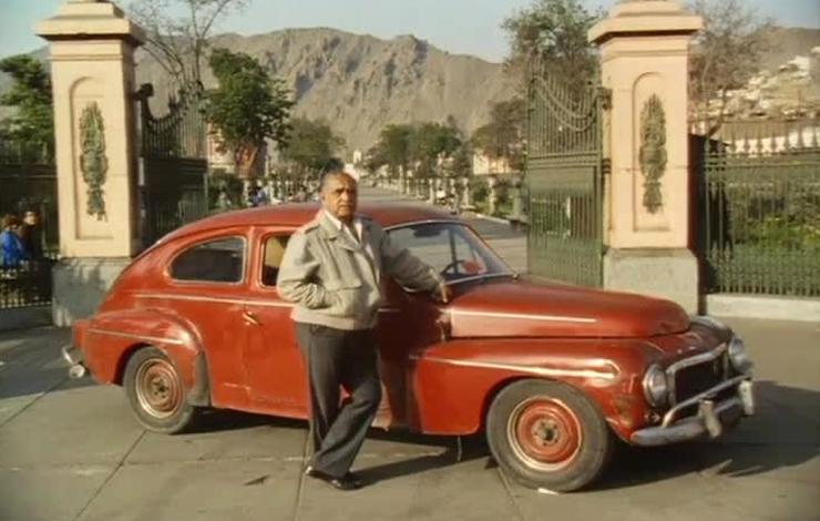 A man stands in front of a red car, from 'Metal and Melancholy', an alternately amusing and touching account of the struggle of impoverished cab drivers in Peru.