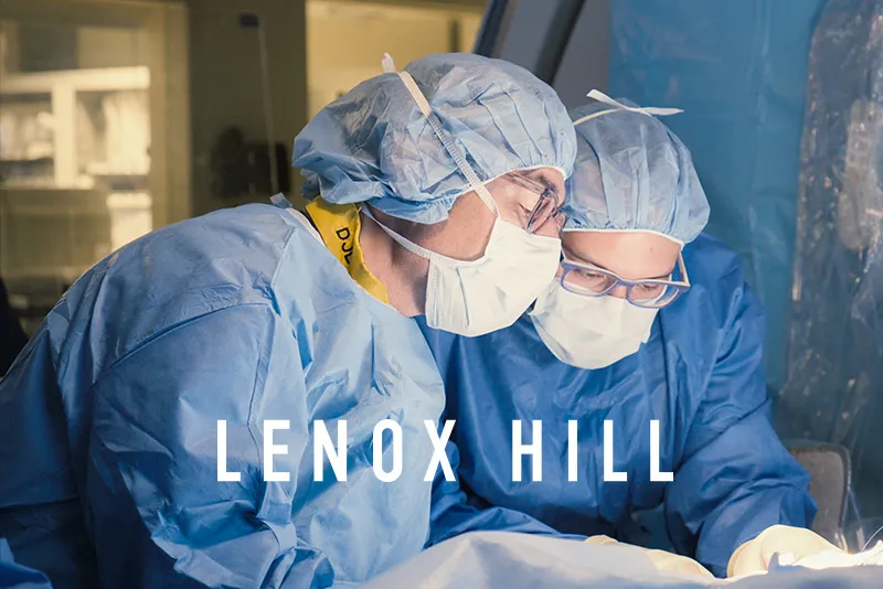 Two doctors in blue scrubs and glasses in an operation.