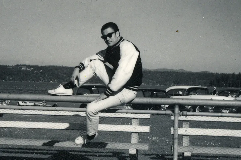 A man is sitting on a ledge in parking lot