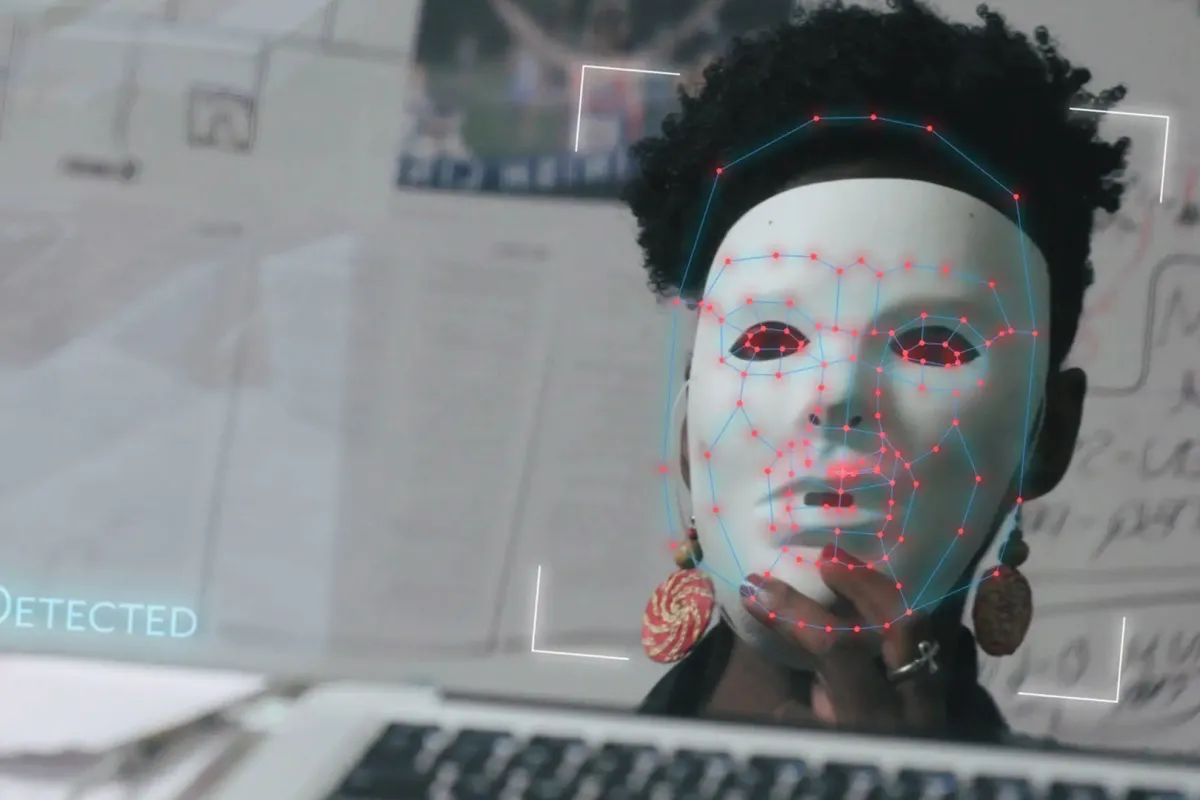 A person wearing a white mask in front of a computer camera
