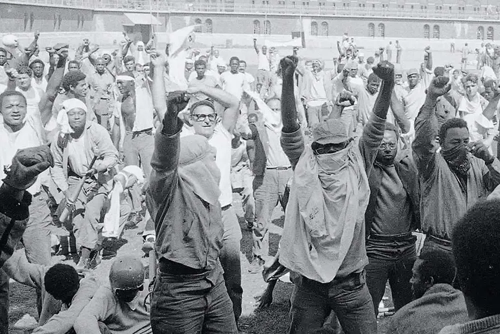 A black and white picture of a group of men with their firsts raised in the air.