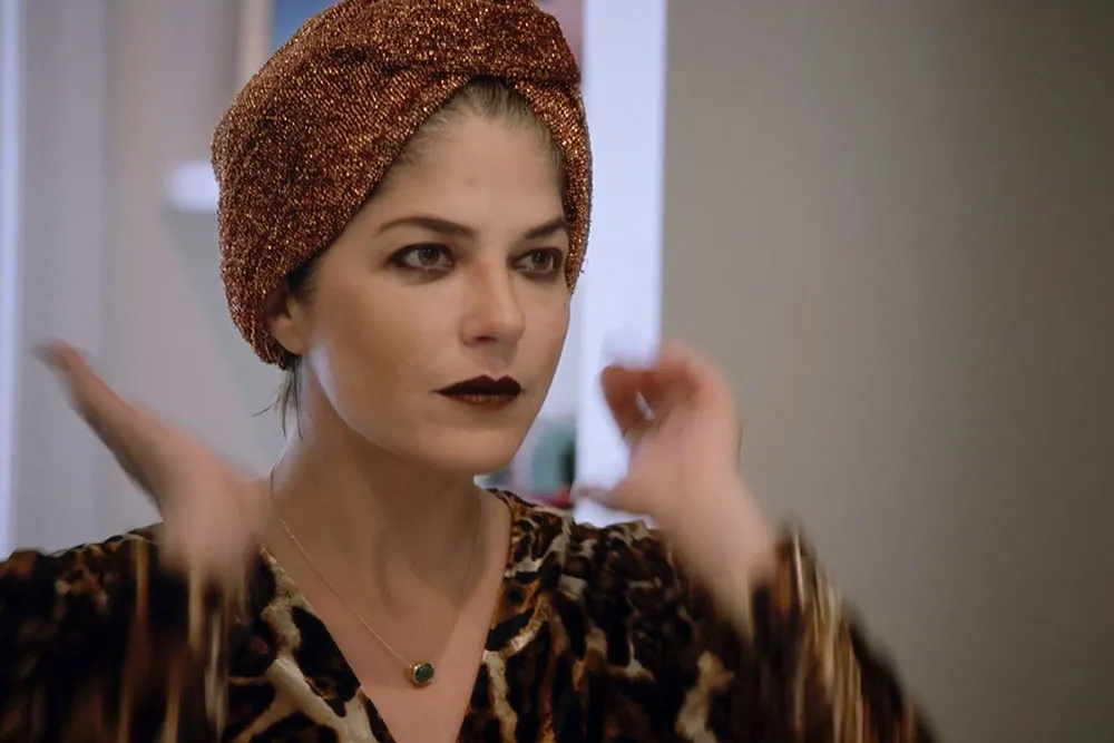 A woman with white skin wearing a head scarf and cheetah print top.