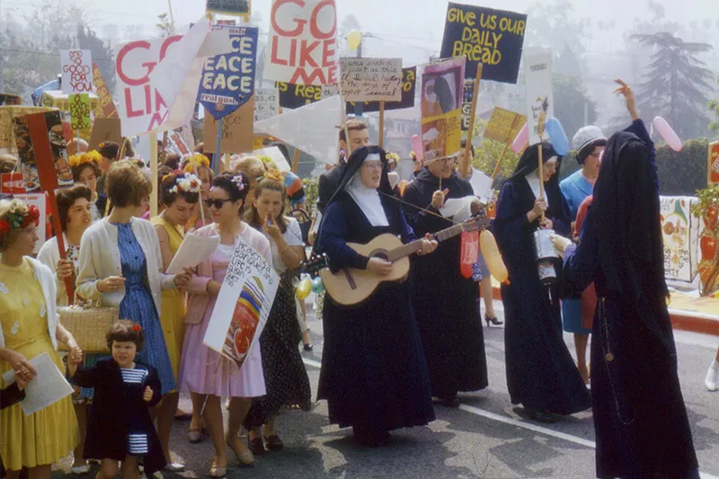 A group of people protesting, including several nuns in black robes.