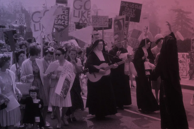 A group of people protesting, including several nuns in black robes.