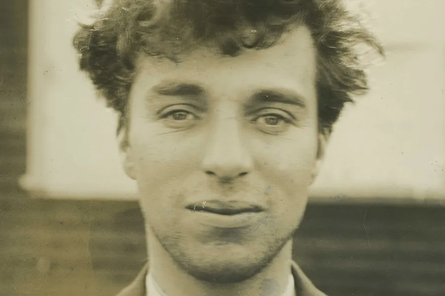 A sepia portrait of a white man with curly light hair.
