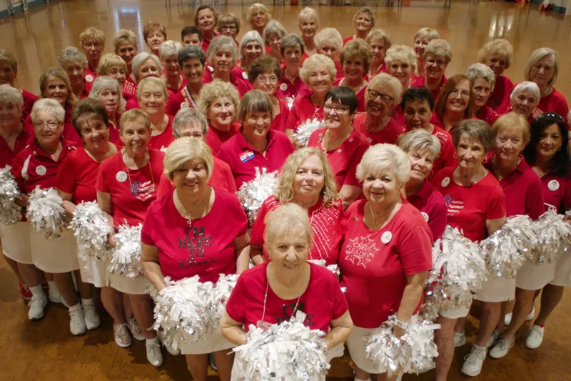 An elderly cheerleading team, all wearing red tshirts and white skirts