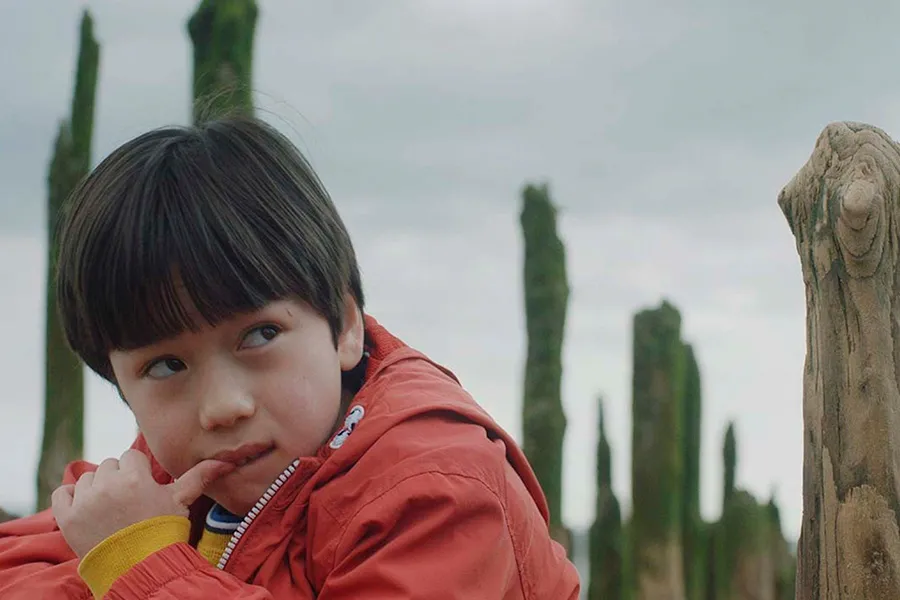 A young boy in an orange coat looking to the side