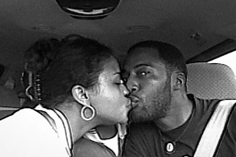Old picture of a Black couple in the car, giving each other a kiss