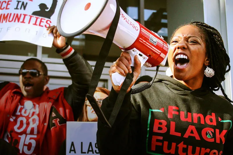 Young Black adults are at a rally, speaking to the megaphone