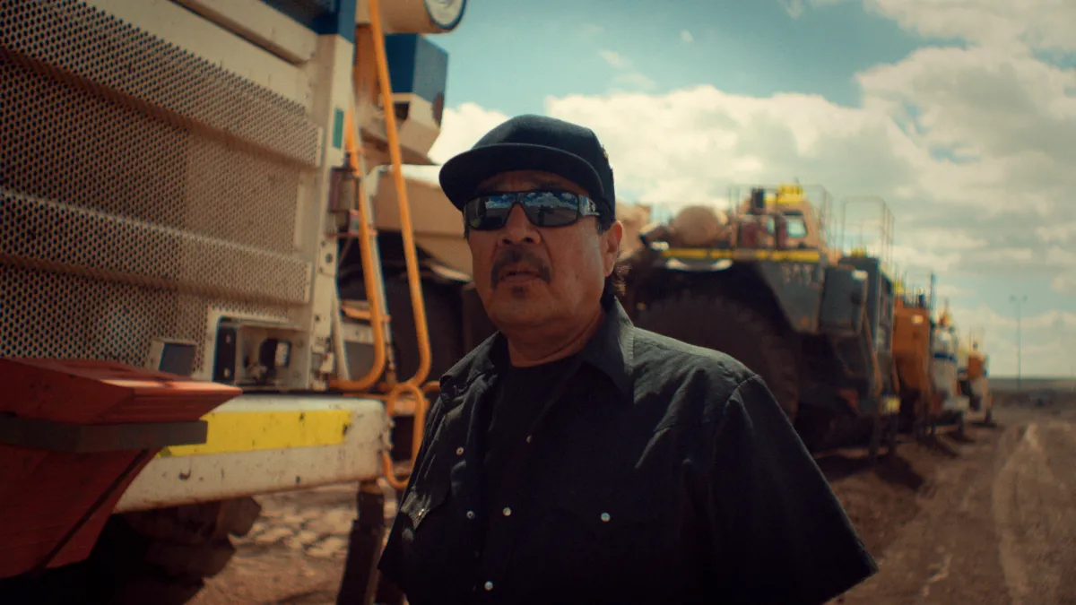 Indigenous coal miner poses for photo in front of plant equiptment