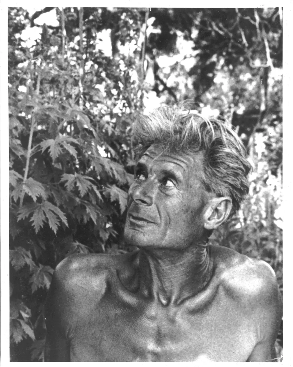 Black and white portrait of Alan Chadwick in front of a plant.