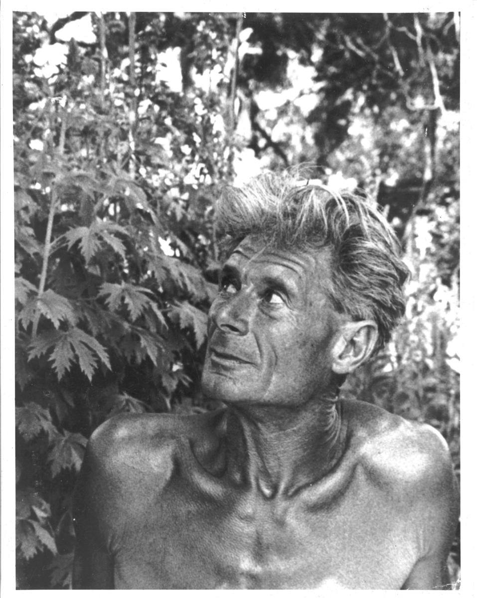 Black and white portrait of Alan Chadwick in front of a plant.