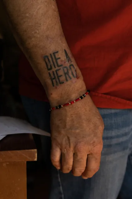 A picutre of a person's arm with 'Die a Hero' tattooed on it.