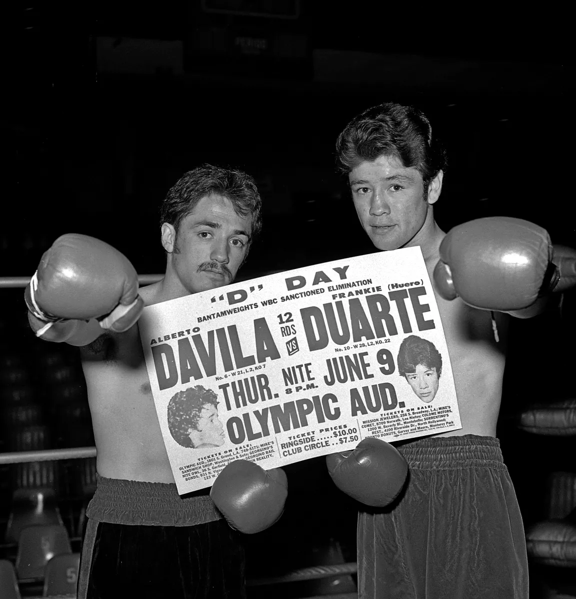 Black and white photo of two boxers holding a newspaper