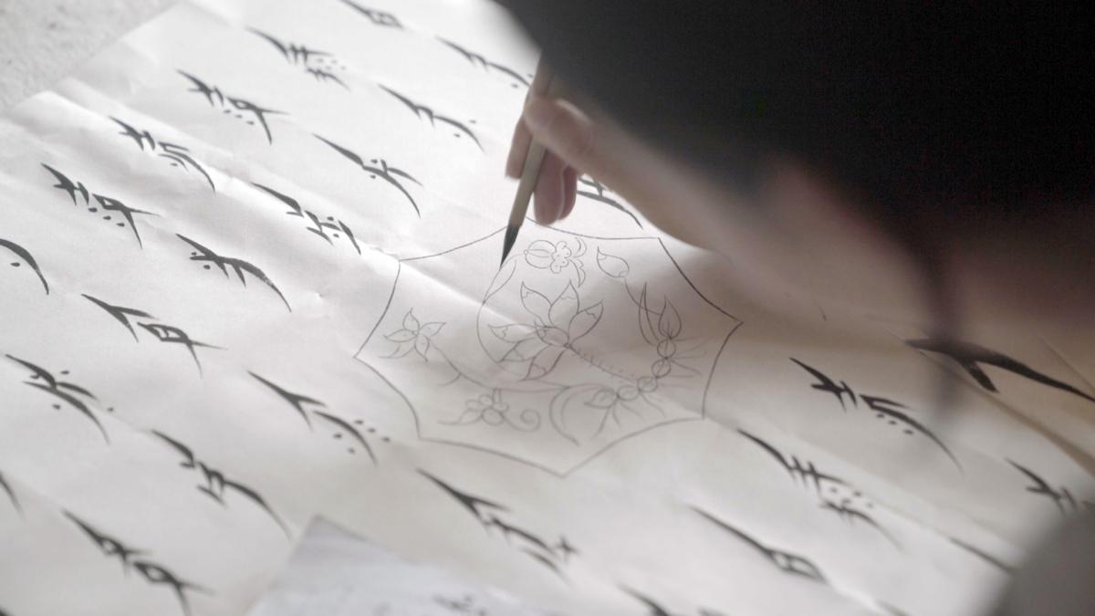 Hu xin writes Nushu characters with a small paint brush. 