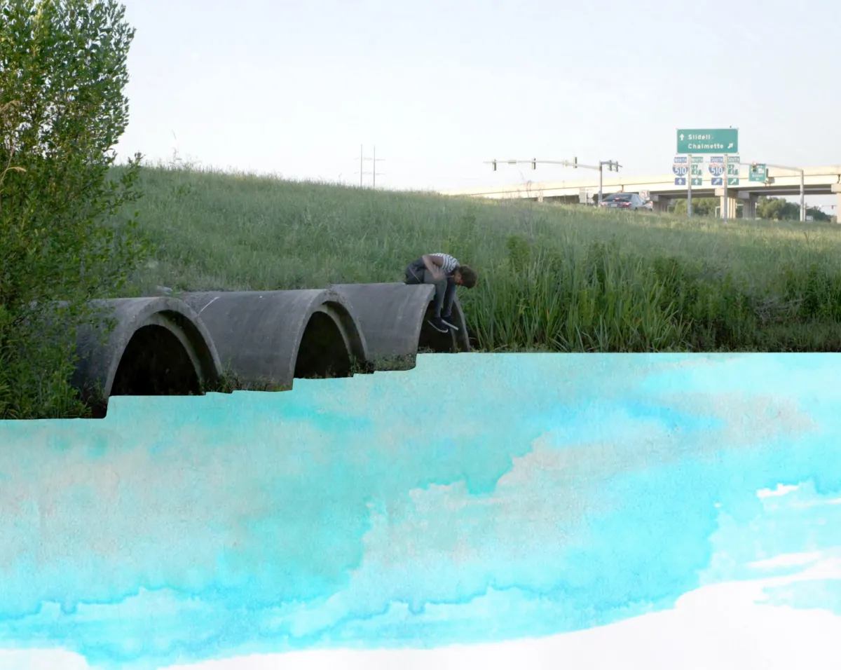 young boy sitting on top of one of three drainage tunnels expelling blue water color paint