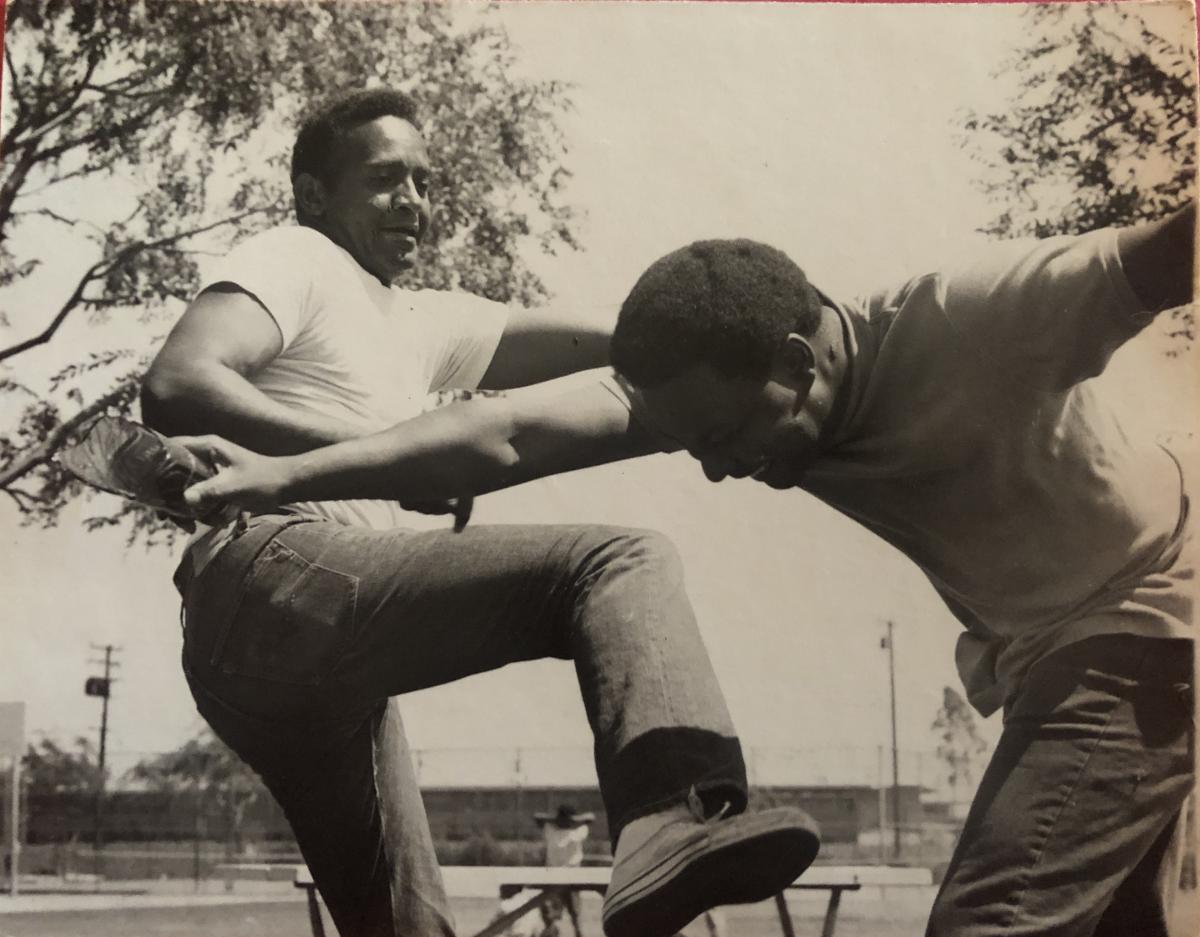 A black and white photo of two African-American man showcasing their stunts.