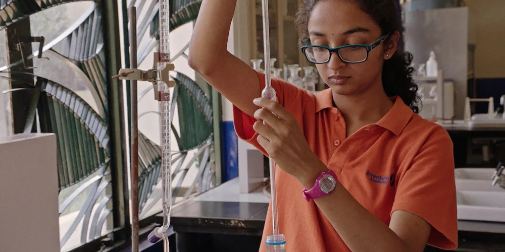 A student is in lab extracting a liquid using a syringe. 