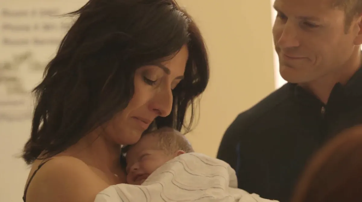 Mother swaddles her newborn who was conceived through surrogacy. 